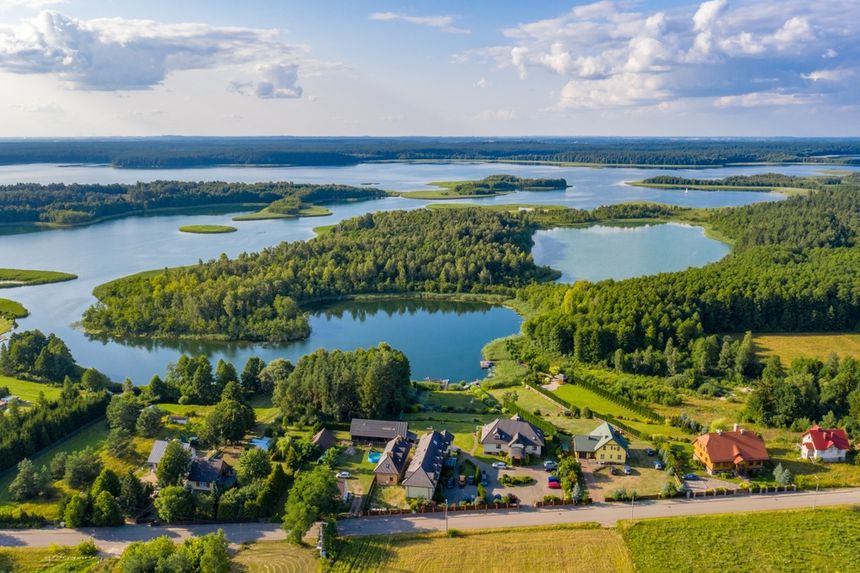 Malownicza panorama z jeziorami i lasami, z domami w dolnej części zdjęcia.