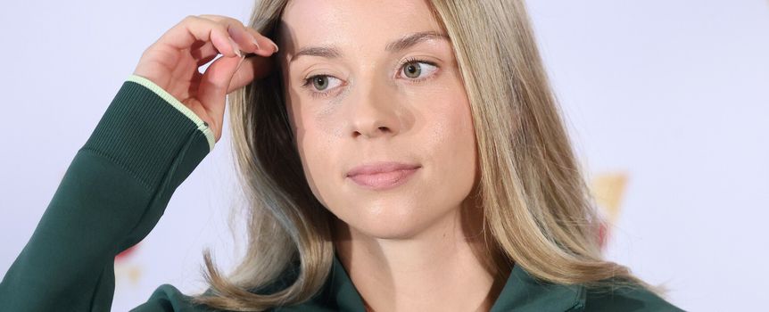 Maja Chwalińska w zielonym dresie, z długimi, prostymi włosami, dotyka dłonią czoła.
