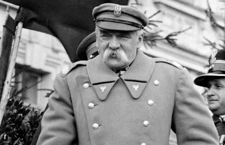Zdjęcie przedstawia mężczyznę w mundurze wojskowym z wąsami, na tle innych oficerów.