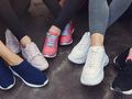 Buty sportowe na bruku. Widać wiele stylów i wzorów obuwia.