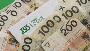 Na zdjęciu widać banknoty polskie oraz kopertę z logo ZUS. Dominują nominały 100 i 200 złotych.