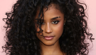 Na zdjęciu portret młodej kobiety z ciemnymi, kręconymi włosami na różowym tle.