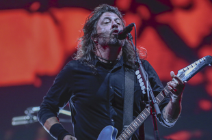 Foo Fighters - Dave Grohl, grający na gitarze i śpiewający do mikrofonu na scenie.