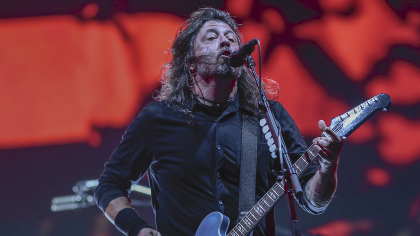 Foo Fighters - Dave Grohl, grający na gitarze i śpiewający do mikrofonu na scenie.