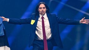 Mężczyzna w garniturze z długimi włosami, trzyma flagę, z napisem „I ❤️ Europe”.
