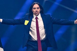 Mężczyzna w garniturze z długimi włosami, trzyma flagę, z napisem „I ❤️ Europe”.