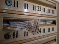 Widok skrzynek pocztowych z kartką wystającą z jednej z nich.