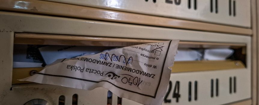 Widok skrzynek pocztowych z kartką wystającą z jednej z nich.