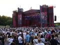 Tłum ludzi na koncercie przed dużą sceną z efektami świetlnymi.