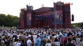 Tłum ludzi na koncercie przed dużą sceną z efektami świetlnymi.
