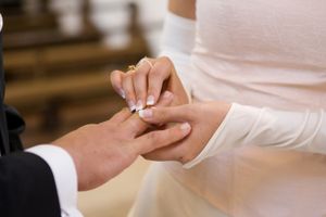 Zdjęcie przedstawia parę młodą wymieniającą obrączki podczas ceremonii ślubnej.