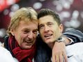 Zbigniew Boniek i Robert Lewandowski przytulają się, celebrując radośnie. W tle rozmyte kolory i konfetti.
