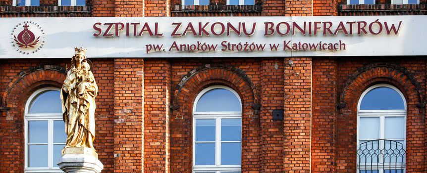 Szpital Zakonów Bonifraterskich w Katowicach, z figurą Matki Boskiej na tle ceglanej elewacji.