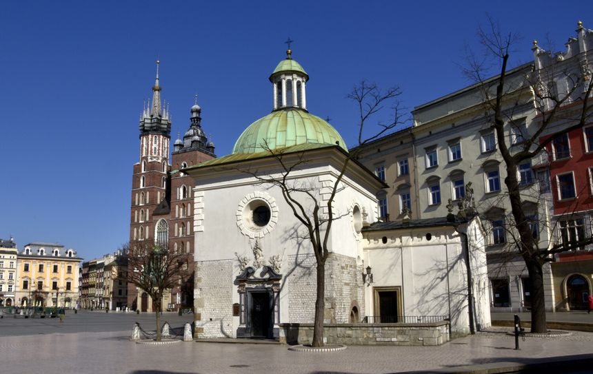 Zabytkowa kaplica z zieloną kopułą na tle nieba i kamienic, w Krakowie, w słoneczny dzień.