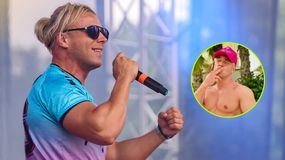 Skolim w kolorowej koszulce, trzymający mikrofon, śpiewa na scenie. W tle zamazane światła.