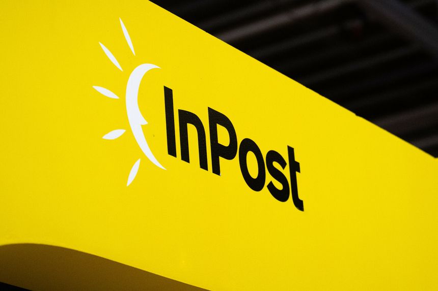 Logo firmy InPost na żółtym tle. Symbol słońca obok napisu.
