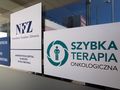 Logo NFZ oraz szybkiej terapii onkologicznej na tle budynku szpitala w Białymstoku.