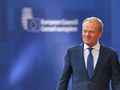 Mężczyzna w garniturze uśmiecha się na tle niebieskiej ścianki z logo Rady Europejskiej.