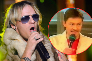 Mężczyzna w okularach przeciwsłonecznych śpiewa na scenie, wokół intensywne światła.