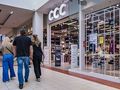 Grupa ludzi spacerująca w galerii handlowej, obok sklepu CCC. Jasne wnętrze i wystawy.