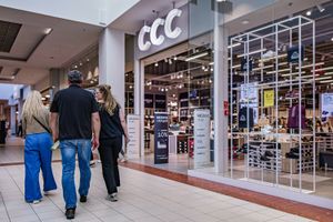 Grupa ludzi spacerująca w galerii handlowej, obok sklepu CCC. Jasne wnętrze i wystawy.