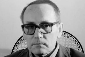 Zdjęcie przedstawia mężczyznę w okularach, z poważnym wyrazem twarzy, na tle jasnej ściany.