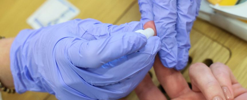 Na zdjęciu widoczne są ręce w rękawiczkach zakładające urządzenie na palec.