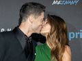 Robert Lewandowski i Anna Lewandowska w eleganckich strojach całują się na czerwonym dywanie.