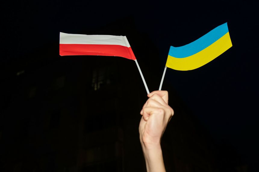Dłoń trzymająca flagę Polski i flagę Ukrainy