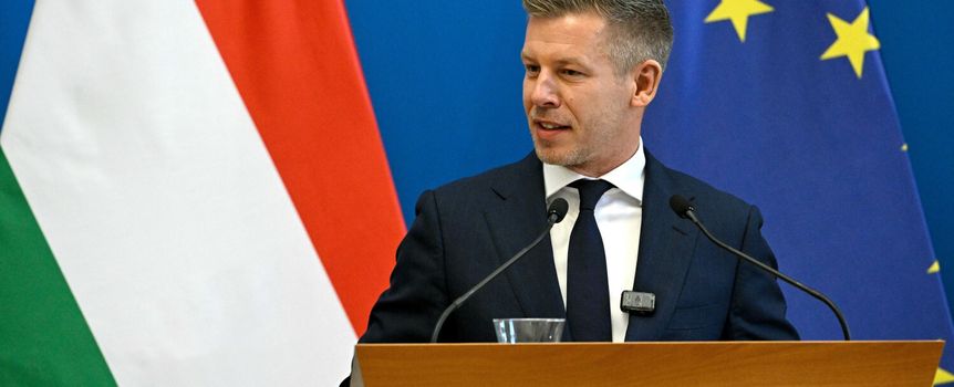 Mężczyzna przy mównicy, za nim flagi Węgier i UE, przemawia na konferencji prasowej.