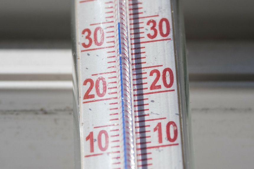 Termometr stojący na tle okna, wskazujący temperaturę około 20 stopni Celsjusza.