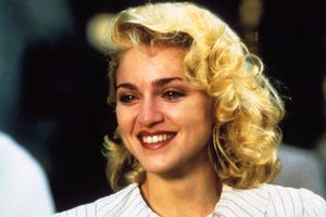 Kobieta z kręconymi blond włosami, uśmiechająca się, w jasnej bluzce.