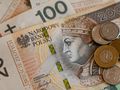 Zestaw polskich banknotów i monet leżących na stole. Banknot 200 zł w centralnej części.
