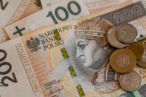 Zestaw polskich banknotów i monet leżących na stole. Banknot 200 zł w centralnej części.