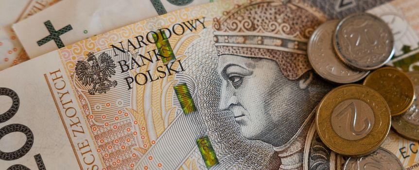 Zestaw polskich banknotów i monet leżących na stole. Banknot 200 zł w centralnej części.