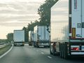 Na zdjęciu widać kilka ciężarówek na autostradzie w wydaniu porannej mżawki.