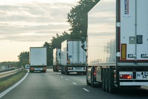 Na zdjęciu widać kilka ciężarówek na autostradzie w wydaniu porannej mżawki.