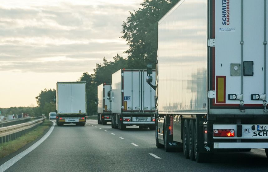 Na zdjęciu widać kilka ciężarówek na autostradzie w wydaniu porannej mżawki.