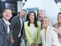 Grupa osób uśmiecha się do aparatu w studio telewizyjnym, robiąc selfie.