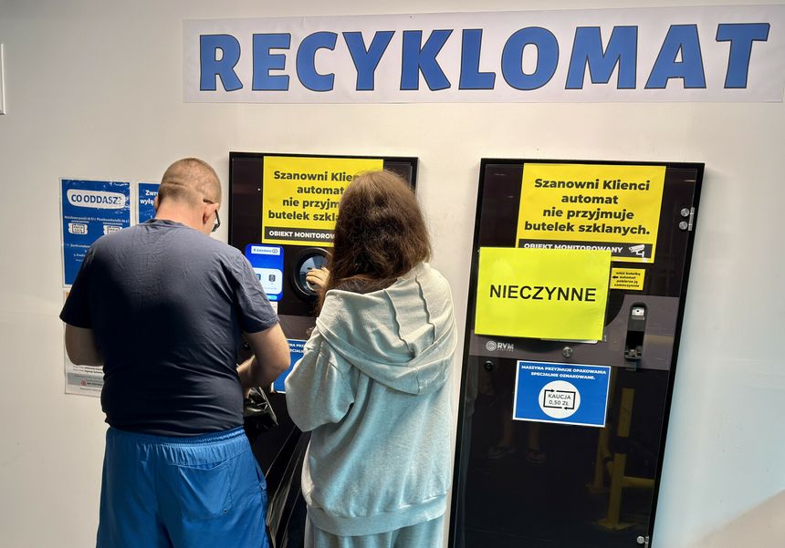 Para ludzi korzysta z recyklo­mat­u z wyraźnymi informacjami o jego nieczynności.