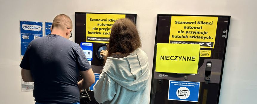 Para ludzi korzysta z recyklo­mat­u z wyraźnymi informacjami o jego nieczynności.