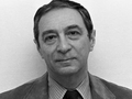 Nie wiem, kto jest na zdjęciu. Opis ALT: Mężczyzna w garniturze, z poważnym wyrazem twarzy, na tle.