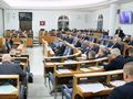 Posiedzenie w sali sejmowej, politycy siedzą w rzędach, jeden mówca przy mównicy.