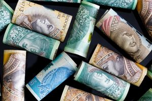 Zdjęcie zwiniętych banknotów w różnych nominałach, na tle ciemnej powierzchni.