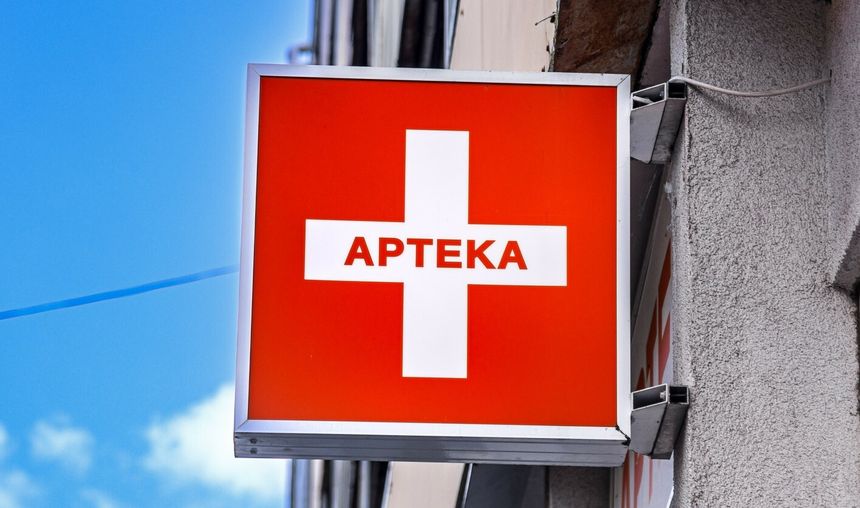 Czerwony szyld z białym krzyżem i napisem 
