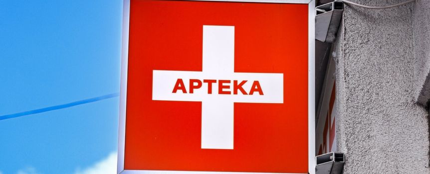 Czerwony szyld z białym krzyżem i napisem 