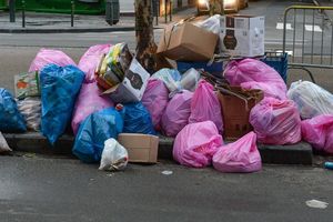 Zgrupowanie kolorowych worków na śmieci i kartonów na chodniku przy ulicy.