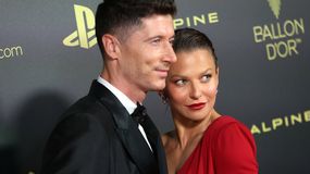 Na zdjęciu Robert Lewandowski z żoną, oboje w eleganckich strojach, pozują na czerwonym dywanie.