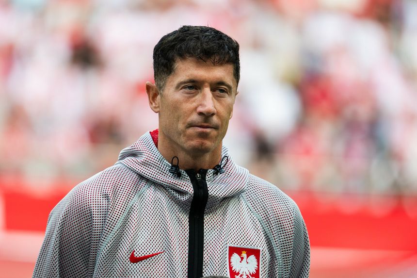 Na zdjęciu mężczyzna w szarej bluzie z kapturem, z flagą Polski na piersi, patrzy w dal.