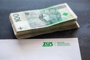 Stos rachunków banknotów 100 zł obok dokumentu ZUS.
